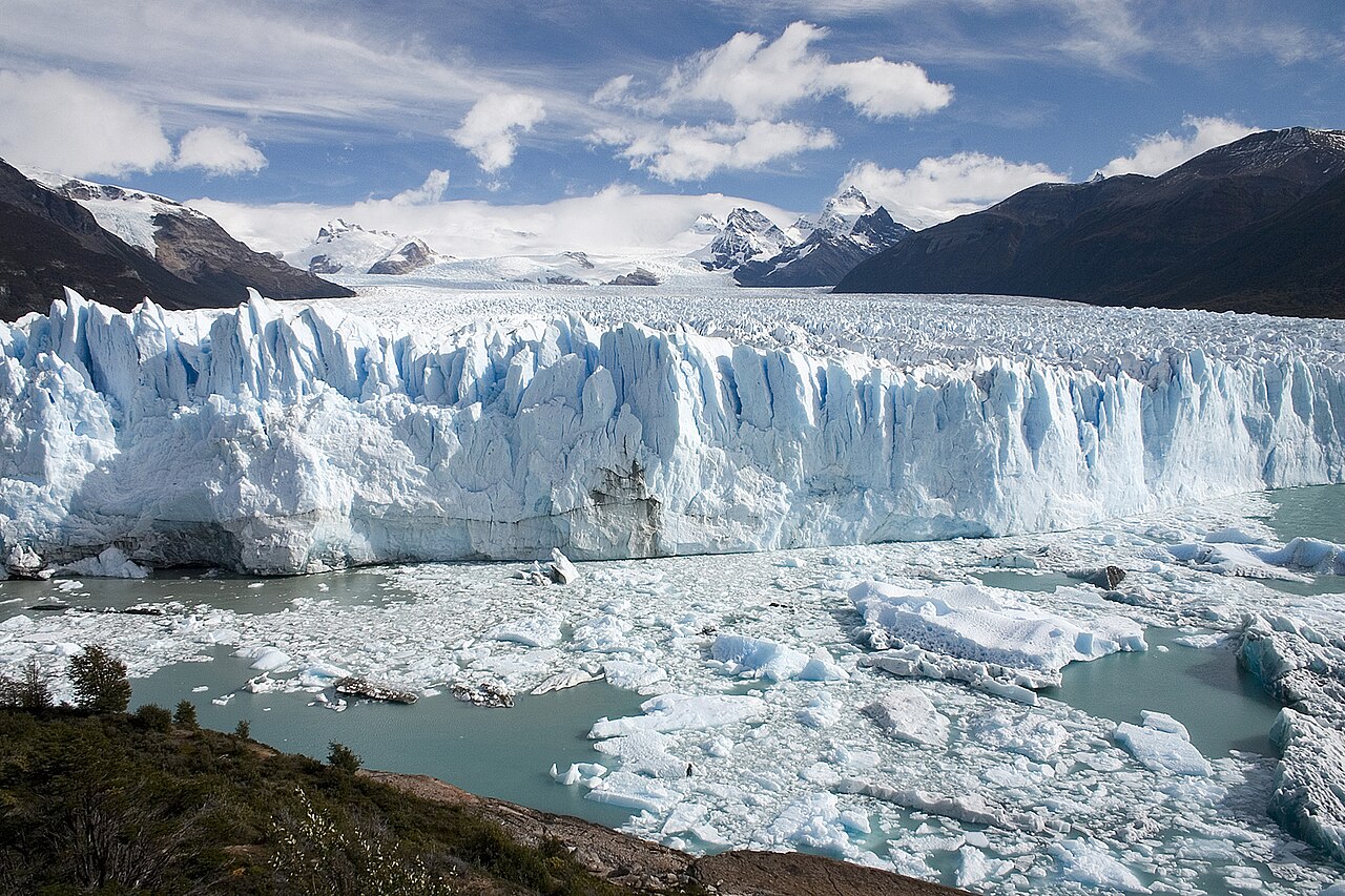Frente de hielo azul de un glaciar que termina en un lago de aguas turquesa con bloques de hielo flotando, en la Patagonia argentina