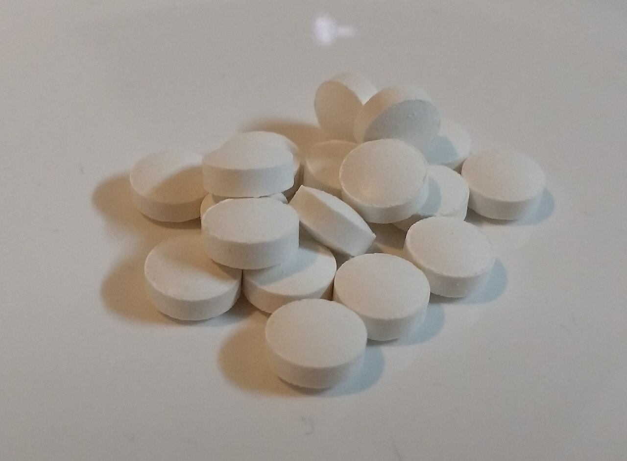 Un puñado de pastillas blancas de vitamina D sobre una superficie clara
