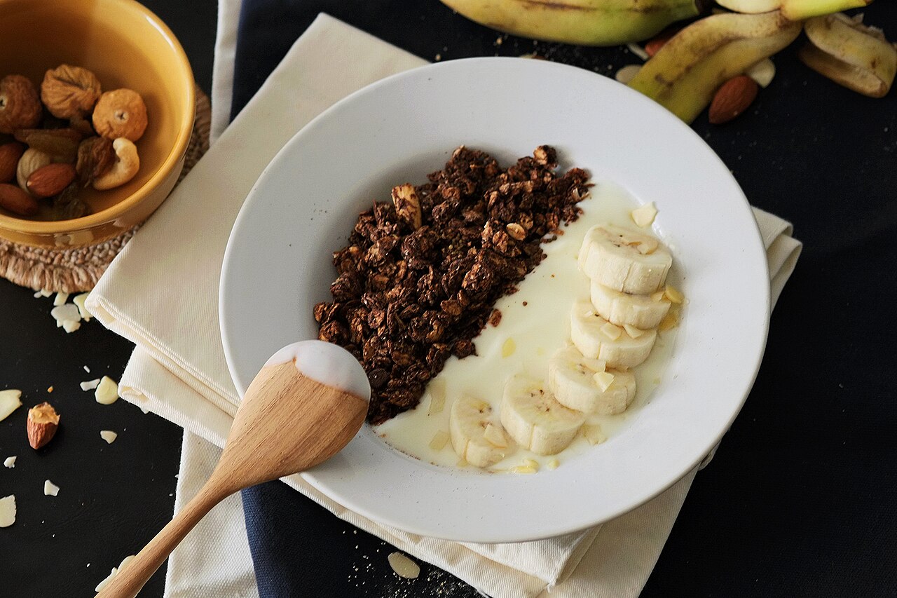 Un bol con yogur, granola y rodajas de plátano, alimentos vinculados a la fibra y la microbiota intestinal