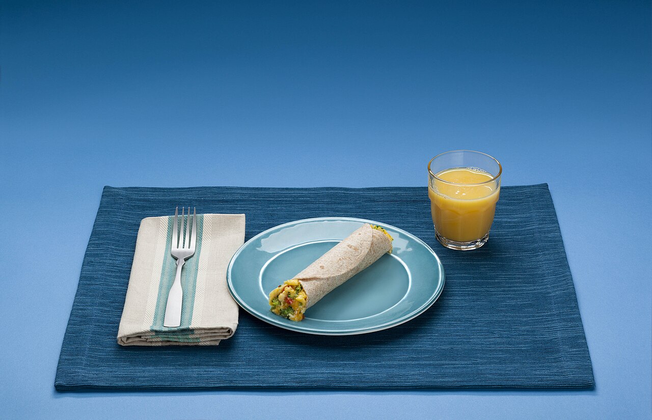 Un plato de desayuno con cereales, alimentos proteicos, lácteos, verduras y fruta