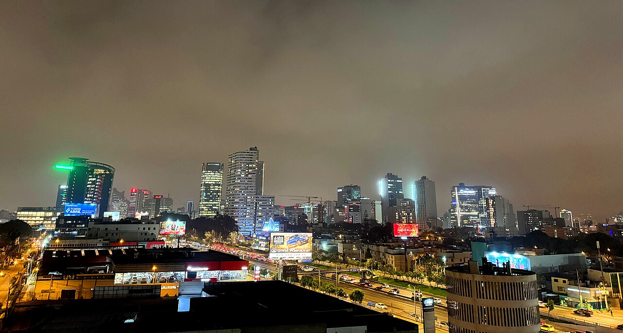 Vista nocturna de los edificios del distrito financiero de San Isidro, en Lima, con una avenida iluminada en primer plano