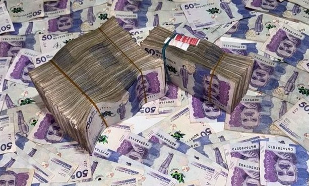 Fajos de billetes colombianos sobre una superficie cubierta de billetes de pesos