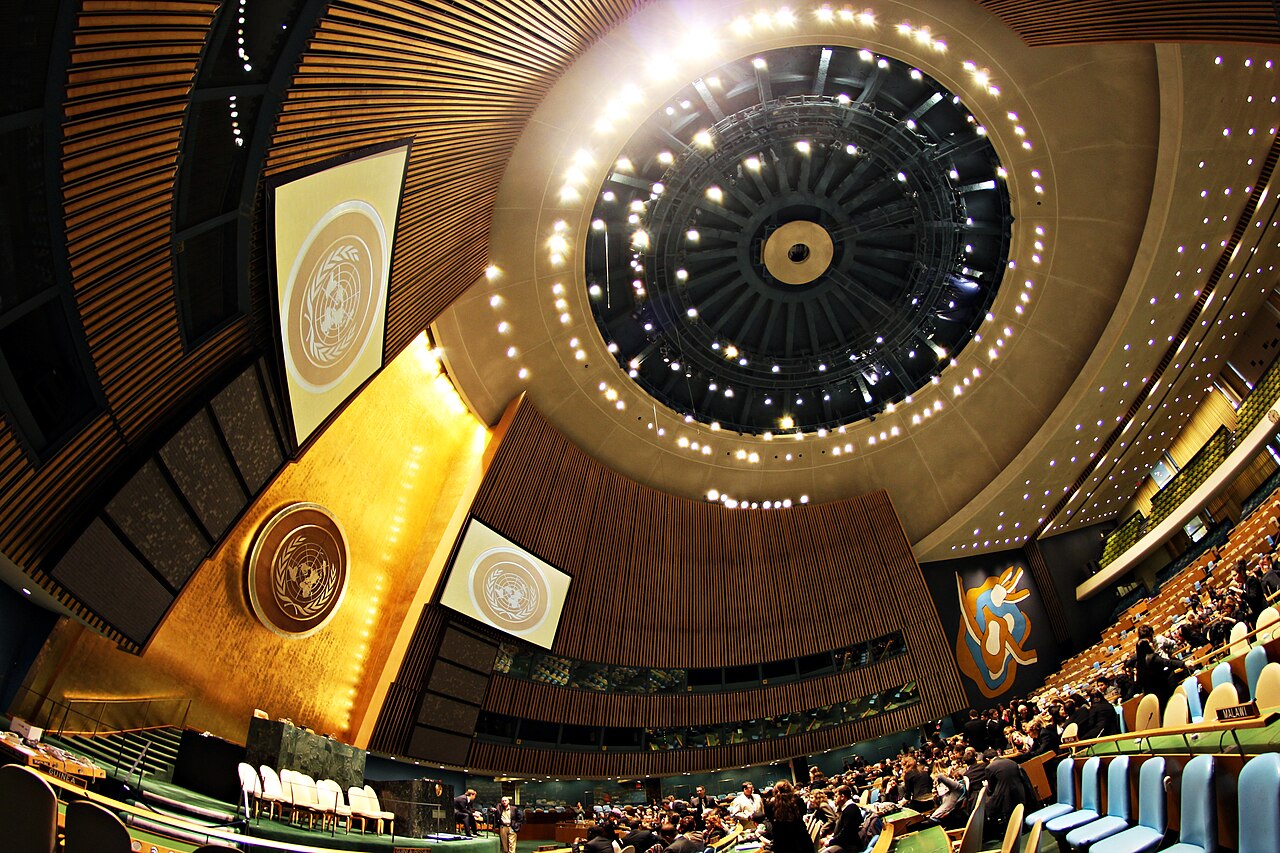 El interior del Salón de la Asamblea General de la ONU en la Sede de Nueva York, con el emblema de la organización sobre la tribuna y delegados en sus escaños