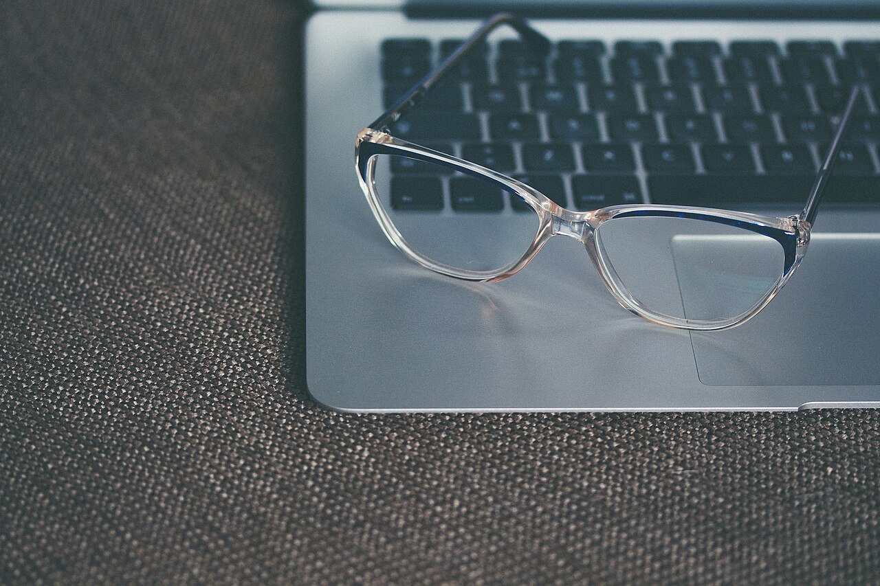 Unas gafas transparentes apoyadas sobre el teclado de un ordenador portátil