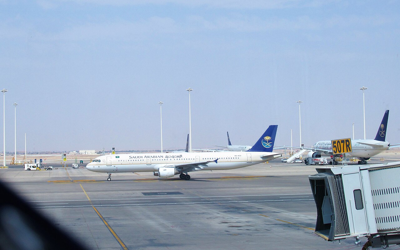 Un avión de Saudi Arabian Airlines rueda por la plataforma del aeropuerto internacional Rey Jalid de Riad, junto a una pasarela de embarque (imagen de archivo de 2019)