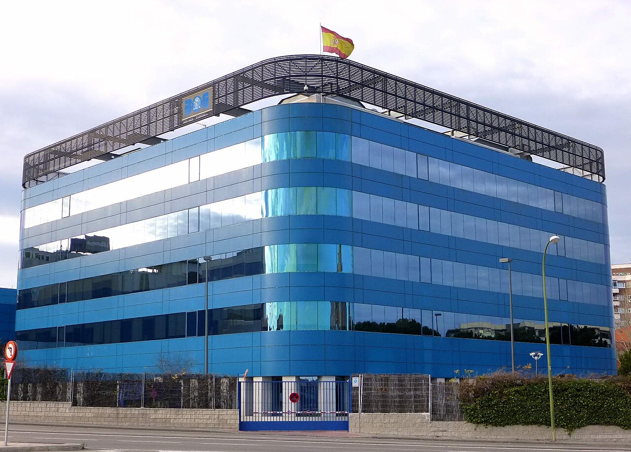 Edificio de cristal azul de la sede del Boletín Oficial del Estado en Madrid, con la bandera de España en la azotea