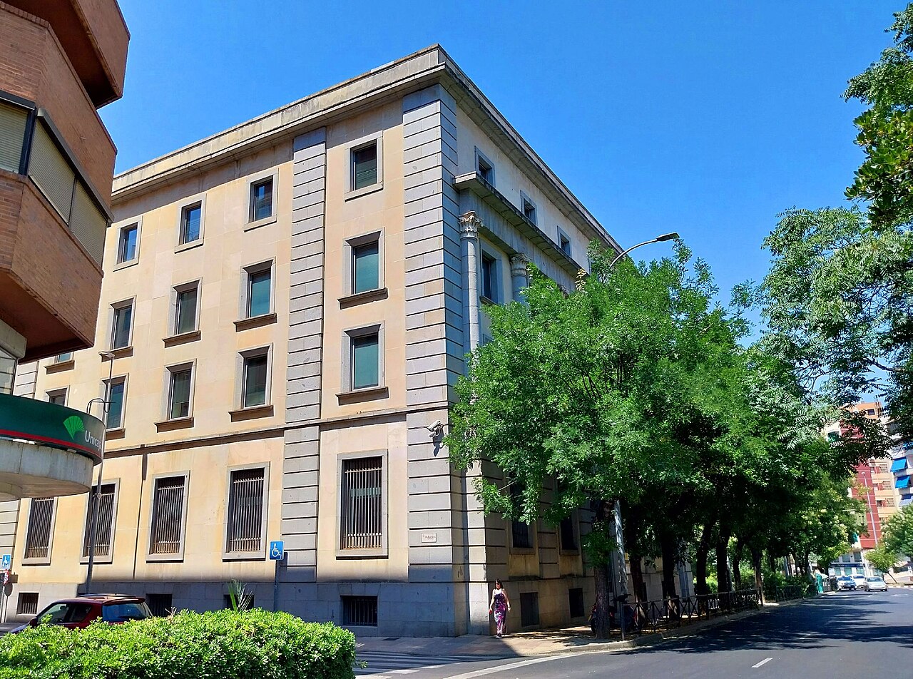Edificio de la sucursal del Banco de España en Cáceres, visto desde una esquina con árboles junto a la calle