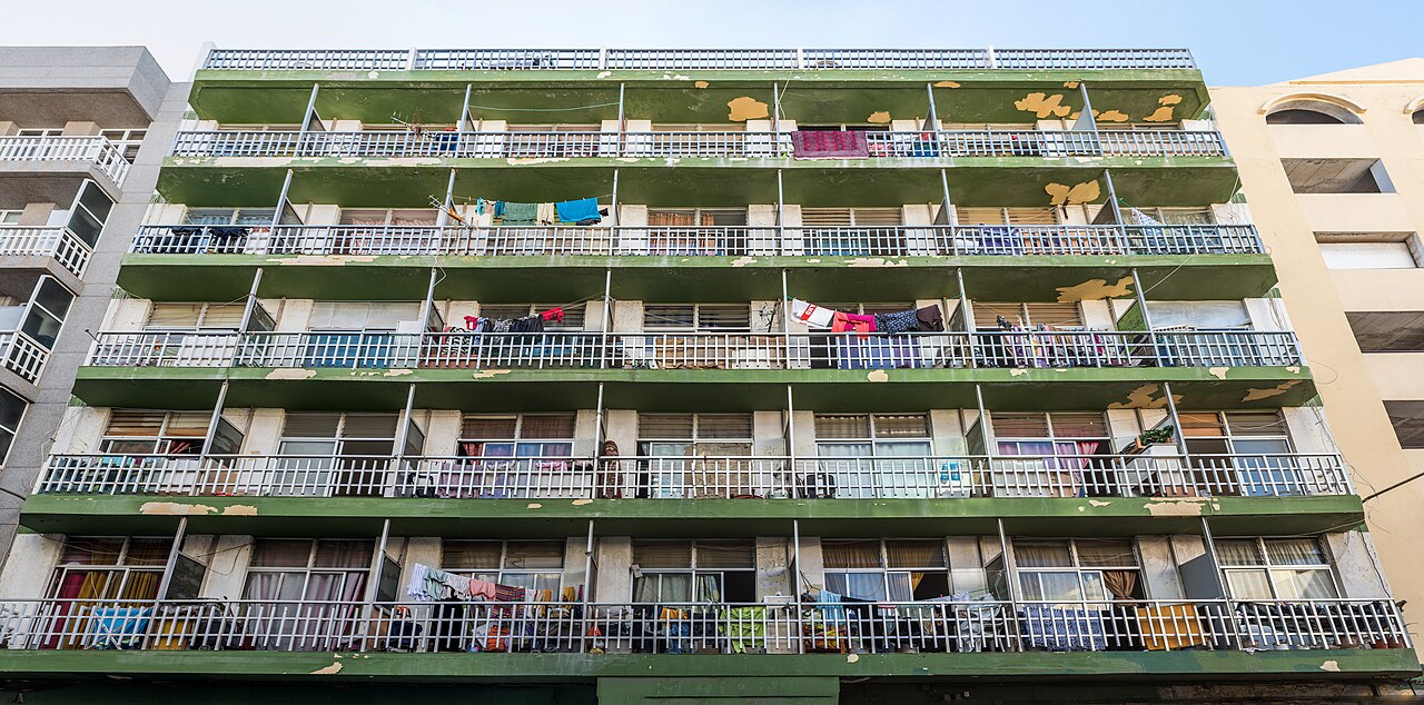 Fachada de un edificio de viviendas de cinco plantas con balcones corridos y ropa tendida en Las Palmas de Gran Canaria