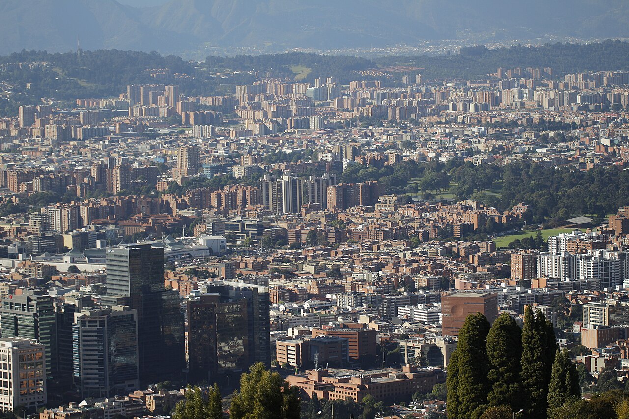 Vista de Bogotá desde un cerro, con torres de oficinas del centro empresarial de Santa Bárbara en primer plano y edificios residenciales hasta las montañas del fondo